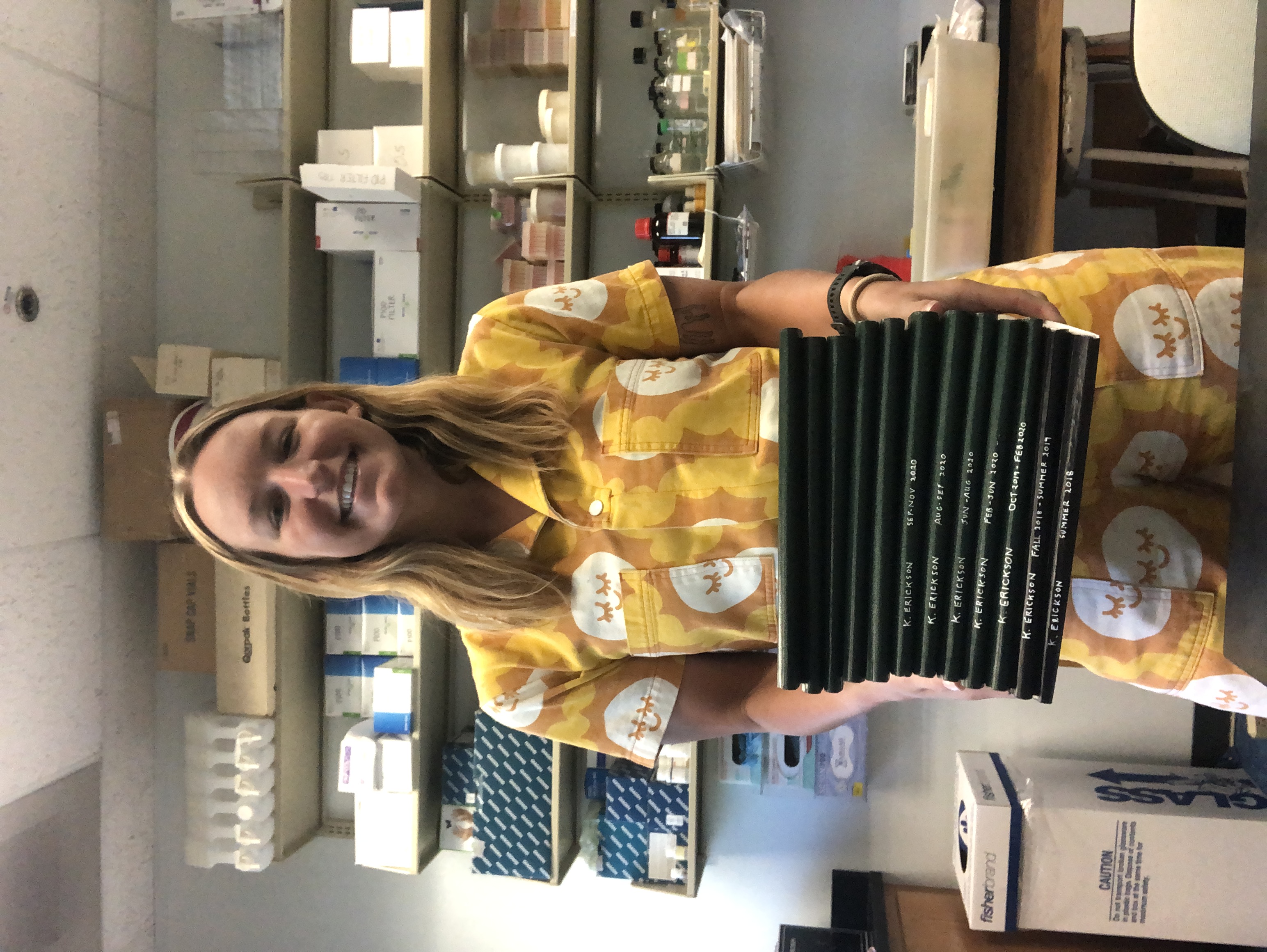 Picture of Katie holding many lab notebooks